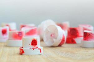 Several plastic nozzles from a paint sprayer that lie on a wooden surface against a gray wall background. The caps are smeared in red paint. The concept of street art and graffiti photo