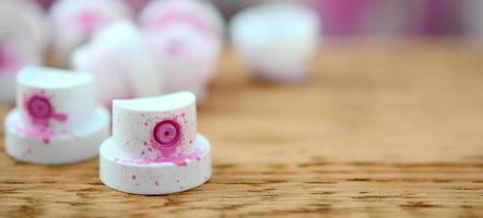 The soiled pink nozzles from the paint sprayer lies on a wooden plank on a background of a many dirty spray cans photo