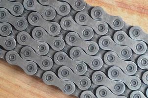 Dirty and oily chain from a mountain bike lying on a wooden table in a bicycle shop photo