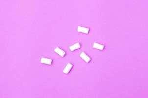 A few chewing gums lie on texture background of fashion pastel purple color paper photo