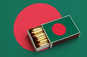 la bandera de bangladesh se muestra en una caja de fósforos abierta, que está llena de fósforos y se encuentra en una bandera grande foto