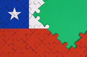 Chile flag is depicted on a completed jigsaw puzzle with free green copy space on the right side photo