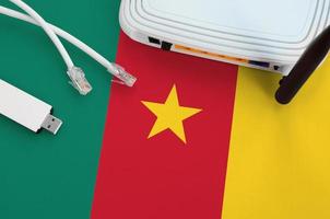 Cameroon flag depicted on table with internet rj45 cable, wireless usb wifi adapter and router. Internet connection concept photo