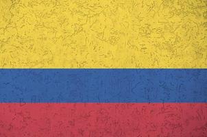 Colombia flag depicted in bright paint colors on old relief plastering wall. Textured banner on rough background photo