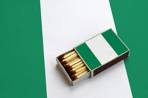 la bandera de nigeria se muestra en una caja de fósforos abierta, que está llena de fósforos y se encuentra en una bandera grande foto