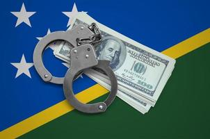 Solomon Islands flag with handcuffs and a bundle of dollars. Currency corruption in the country. Financial crimes photo