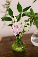 Pink eustoma and white hyacinth flowers in a glass vase in the decor of the house photo