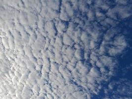 Blue sky background with clouds. Cirro-cumulus clouds on a blue sky on a sunny day. Cirrus sky. Spindrift clouds. photo