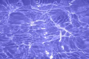 Defocus blurred transparent purple colored clear calm water surface texture with splash, bubble. Shining purple water ripple background. Surface of water in swimming pool. Purple bubble water shine. photo