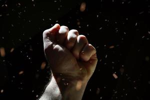 man hand up gesturing in the shadows, dark background photo