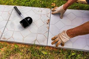 the hands of a worker in gloves lay tiles in a country house, cottage. Landscaping. laying of stone tiles. photo