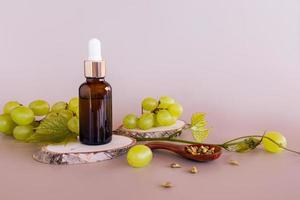 natural organic grape seed oil or whey based on them in a cosmetic bottle with a beige background. product presentation. photo