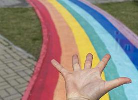 flat hand on the background of rainbow path on city street, copy space photo