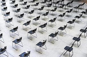 Many black chairs standing indoors at the same distance before the event photo