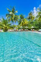 Beautiful vertical beach pool panorama. Palm trees, beach chairs beds with infinity pool close to sea and horizon. Tranquil summer background, travel leisure recreational landscape. Tropical resort