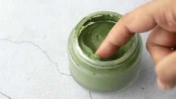 Tauchen Sie einen Finger in eine Tonerdemaske mit grüner Paste video