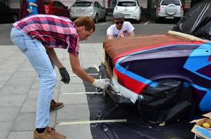 KHARKOV, UKRAINE - MAY 27, 2017 Festival of street art. Young guys draw graffiti on the car body in the city center. The process of drawing color graffiti on a car with aerosol cans photo