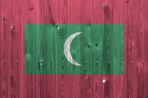 Maldives flag depicted in bright paint colors on old wooden wall. Textured banner on rough background photo