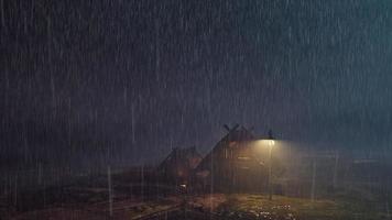 Thatched house and yellow light in the middle of a rainy night in the far distance of the night video