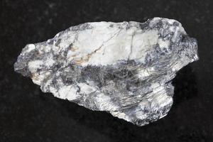 native Bismuthinite in raw quartz stone on dark photo