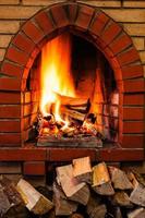 woods pile and burning firewood in brick fireplace photo