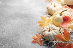 Autumn leaves and pumpkins over  grey concrete background photo