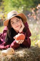 Happy young girl with pumpkin in autumn garden photo