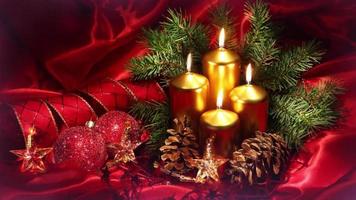 enfeite de natal destacado com quatro velas douradas acesas e bolas e estrelas brilhantes para celebrar a véspera de natal video