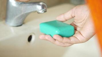 Washing hands at lavatory with teal soap bar video