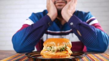 una hamburguesa con queso en un plato frente a un hombre video