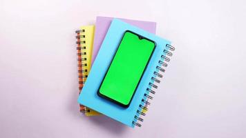 telefoon met groen scherm Aan top van een stack van notebooks video