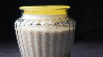 A jar of white cereal, with a yellow lid on black background video