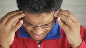 Man wearing glasses touching his forehead in pain, headache, migraines video