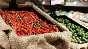 bakken van rood Chili paprika's en limoenen met jute kleding stof Aan Scherm in vers voedsel markt video