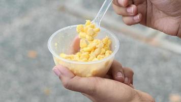 Scooping corn food out of plastic container outside on sidewalk video