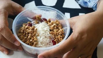 mujer sostiene un vaso de plástico de granola, coco y fruta video