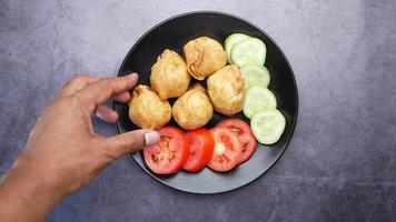 Indian street food singara on plate with tomatoes and cucumbers video