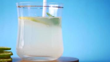 una bebida refrescante, limonada, menta, rodajas de limón sobre fondo azul video