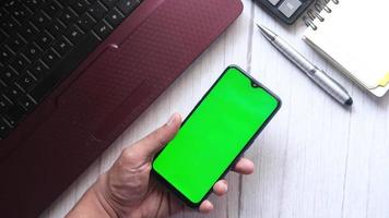 Hand holds a smartphone with a green screen video