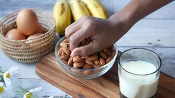 afferrando mandorle con il mano, un' bicchiere di latte, uova e banane video