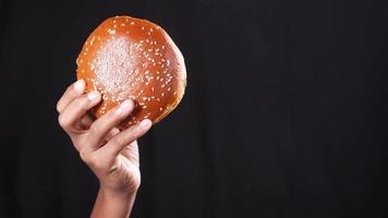 Holding a hamburger high on black background video