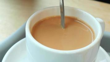 Spoon stirring in cream added to a cup of coffee video