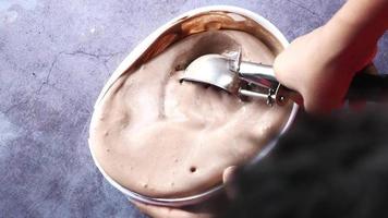 Overhead view of scooping chocolate ice cream out of container
