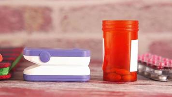 Macro shot of pills blisters, a pill container, blood monitor and a notebook on table video