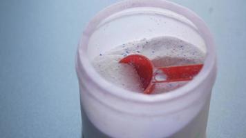 Powdered laundry soap with a red measuring spoon close up video