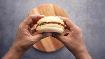 Holding a burger with sesame seed bun