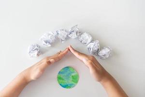 Reutilice el papel para proteger el mundo. reducir la cantidad de uso de papel salvará más árboles. las manos de los niños protegen el mundo. foto