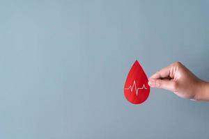 Blood donation concept. Human holding blood sign with heart rate beat. photo