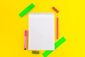 Back to school. Education. Notebook cell for notes, markers, crayons, pencil, ruler on yellow background. Flat lay. Copy space photo