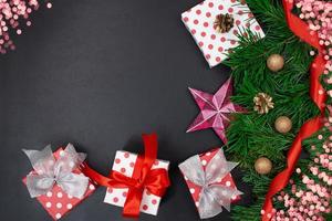 Gift boxes with bows, fir branches, star, ribbon and bokeh on black background. Christmas, New Year. Copy space photo